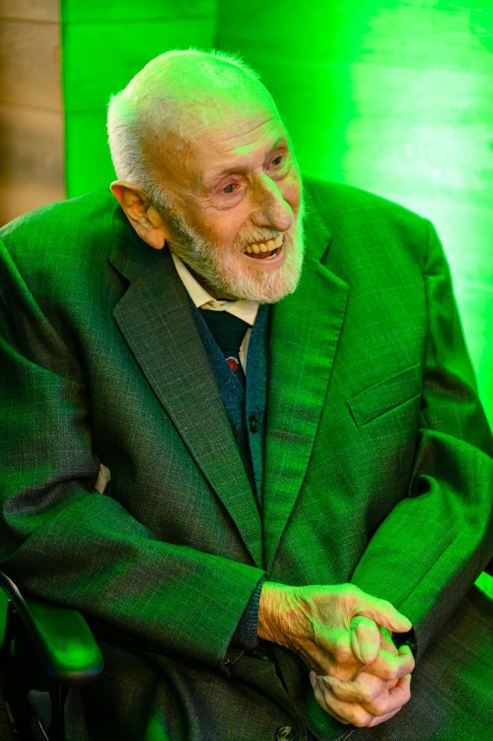 Mike Lowe laughing in a green jacket under green light at the unveiling.